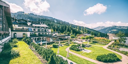 Wellnessurlaub - Pinzgau - Der Sonnengarten macht seinem Namen alle Ehre: auf 2.000 m2 befinden sich nicht nur exklusive grüne Freiflächen mit edlen Liegen, sondern auch eine Piazza mit Loungemöbeln für entspannte Gespräche und romantische Sonnenuntergänge. - Übergossene Alm Resort