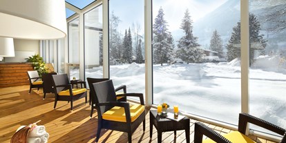 Wellnessurlaub - Wirbelsäulenmassage - Leogang - Wandelgang aus Glas mit Blick auf die schneebedeckten Berge - CESTA GRAND Aktivhotel & Spa